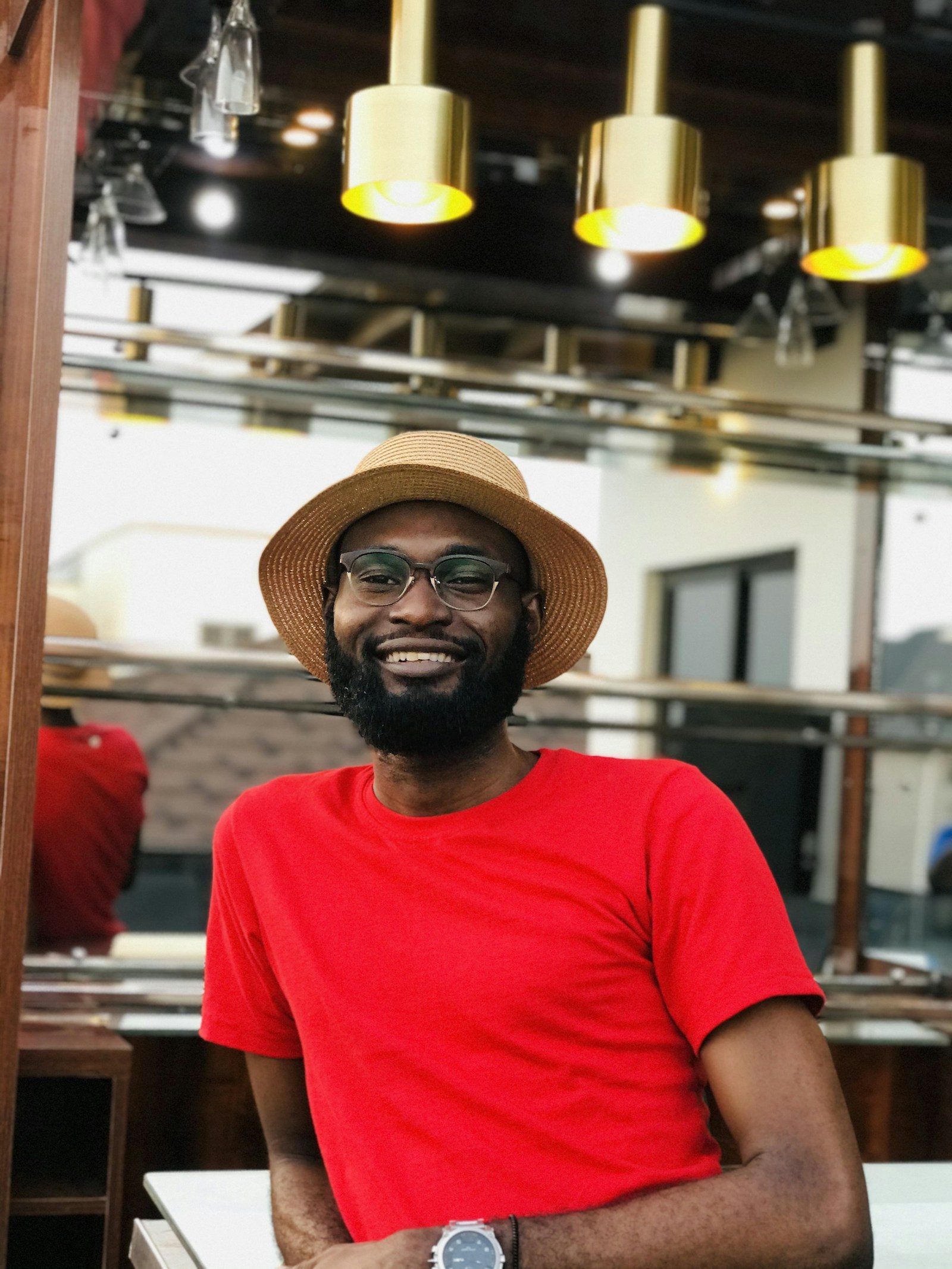 A smiling café owner in a red T-shirt and hat