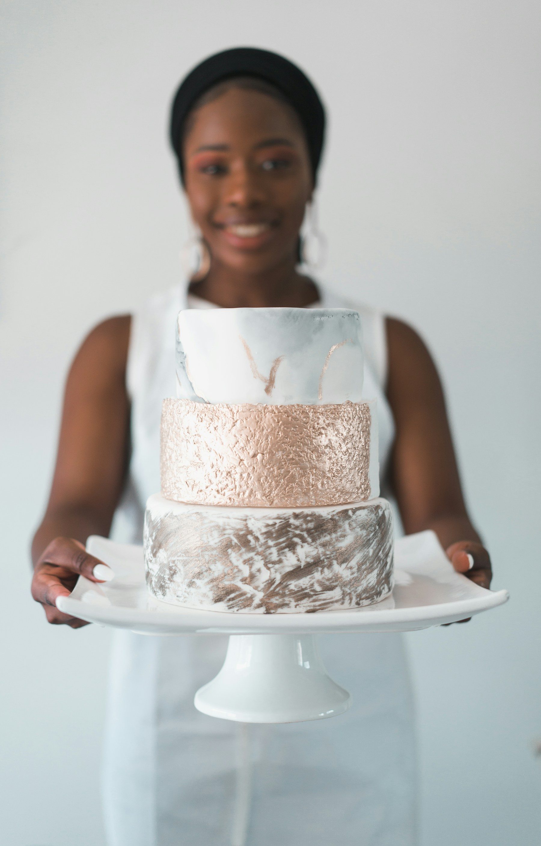 A cake designer holding a two-tier celebration cake