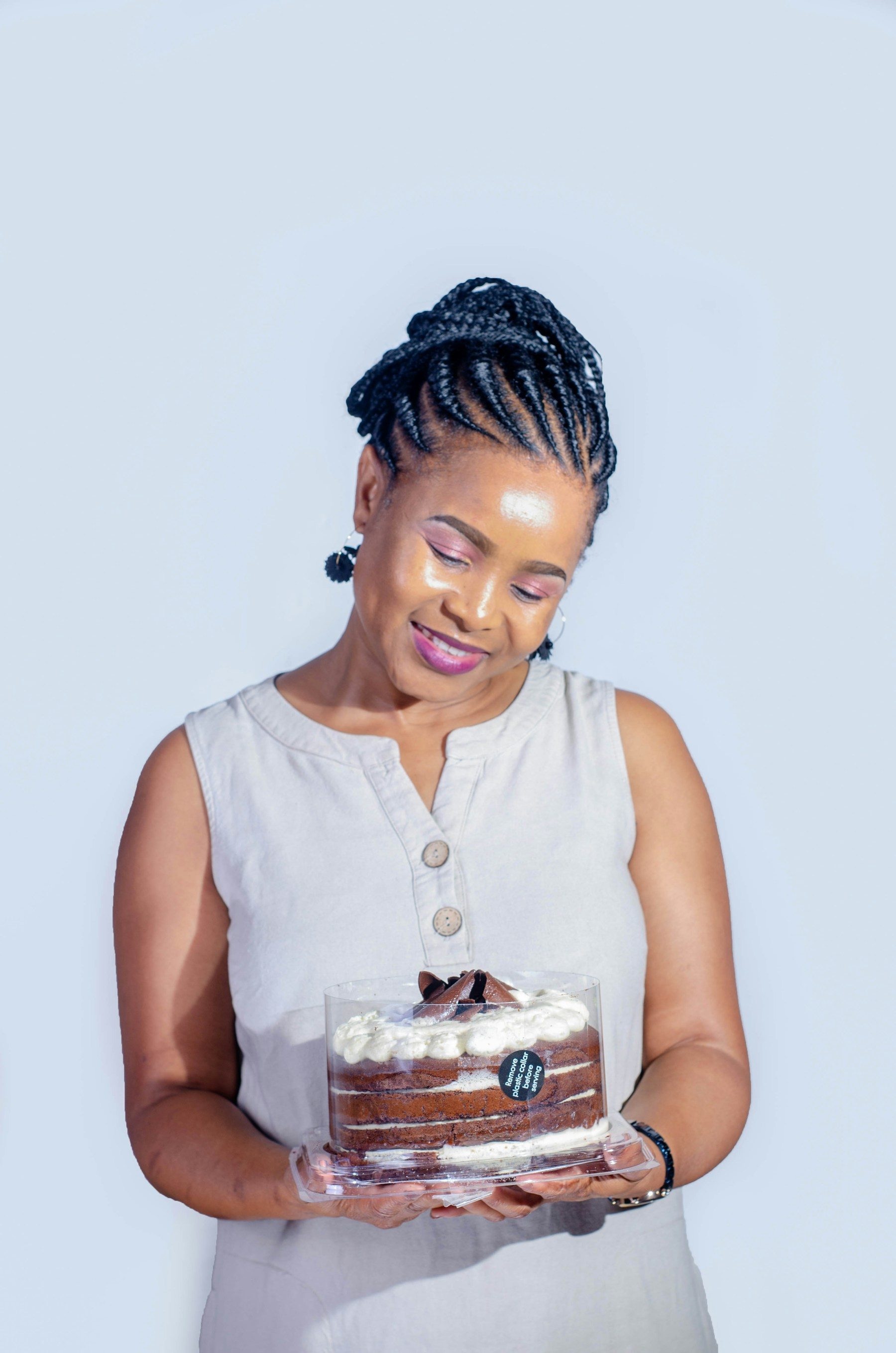 A cake designer smiling as she holds one of her cakes