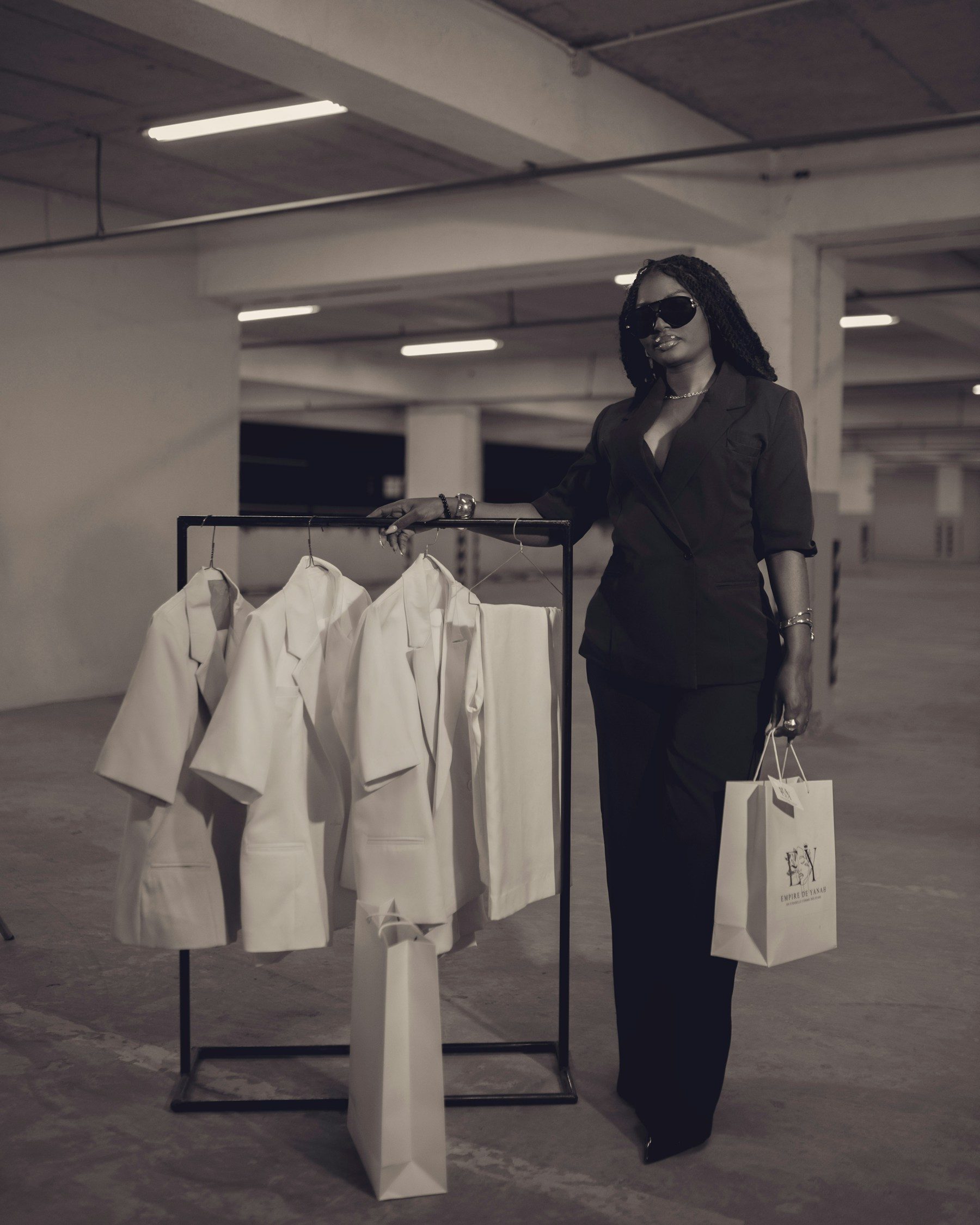 A fashion brand owner with a shopping bag beside her clothing rail